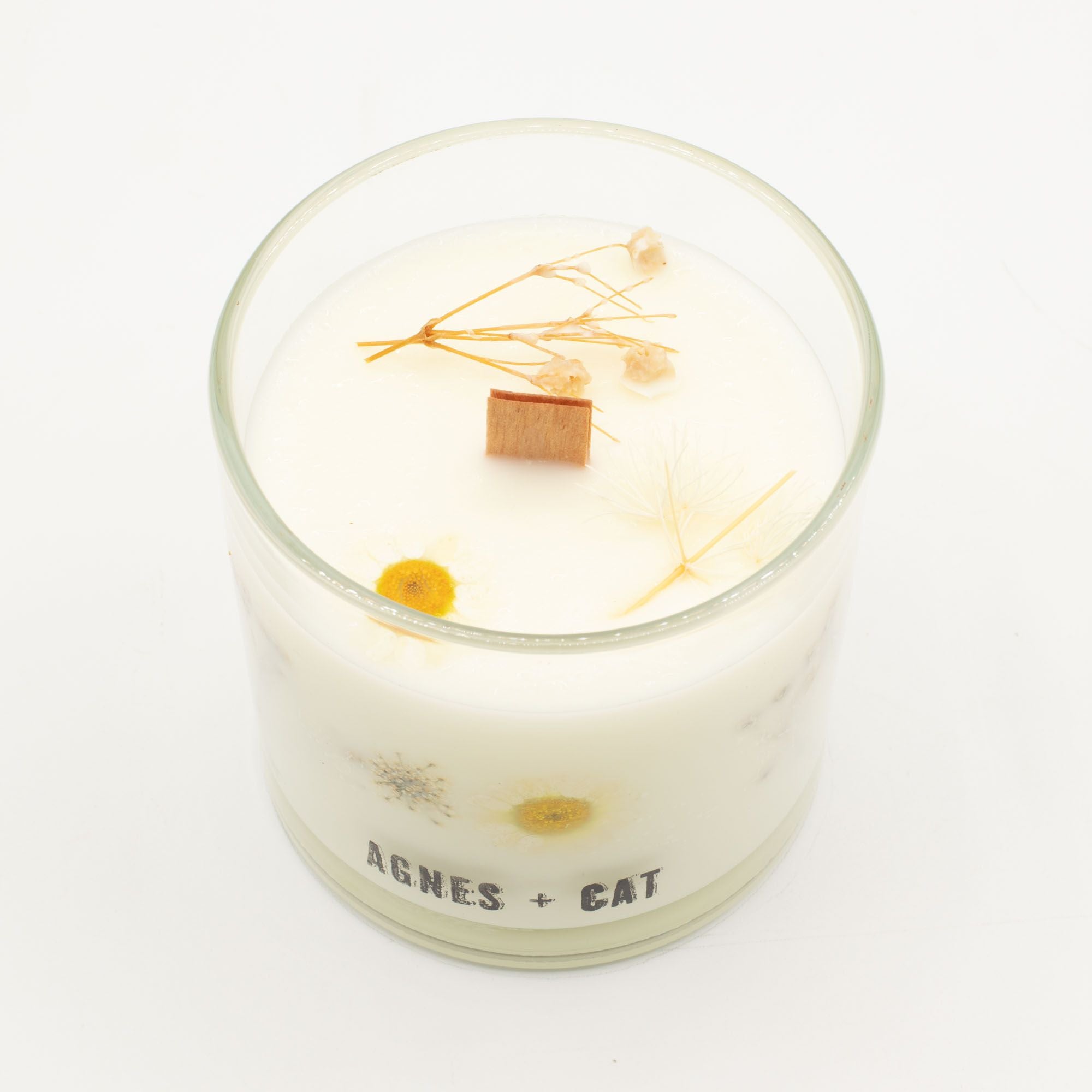 Candle in a glass jar with decorative elements on a white background, featuring the brand 'AGNES + CAT'.